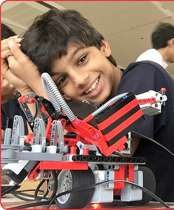 Krishan Sharma smiling beside his robot
