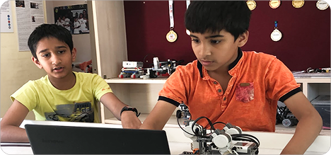 Two students programming a robot on a laptop